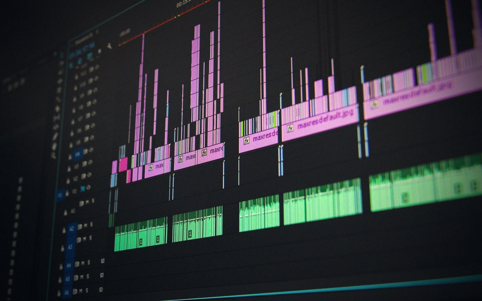 Video editing timeline showing pink audio waveforms and green clips on a dark screen