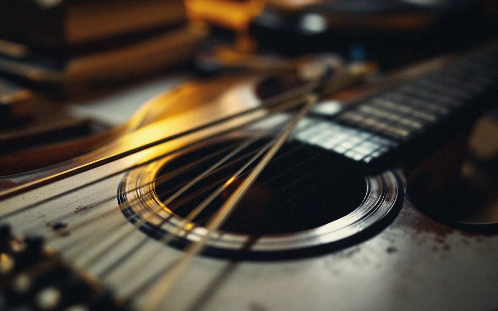 Close-up of an acoustic guitar's soundhole, strings and fretboard in warm light