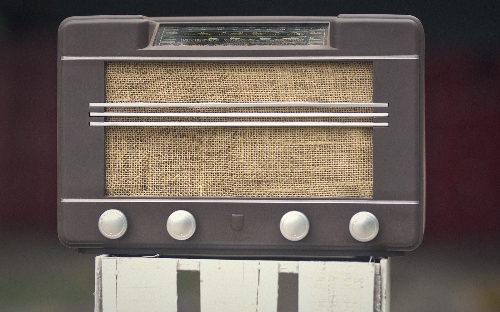 Vintage brown radio with woven speaker grille and four control knobs on wooden stand