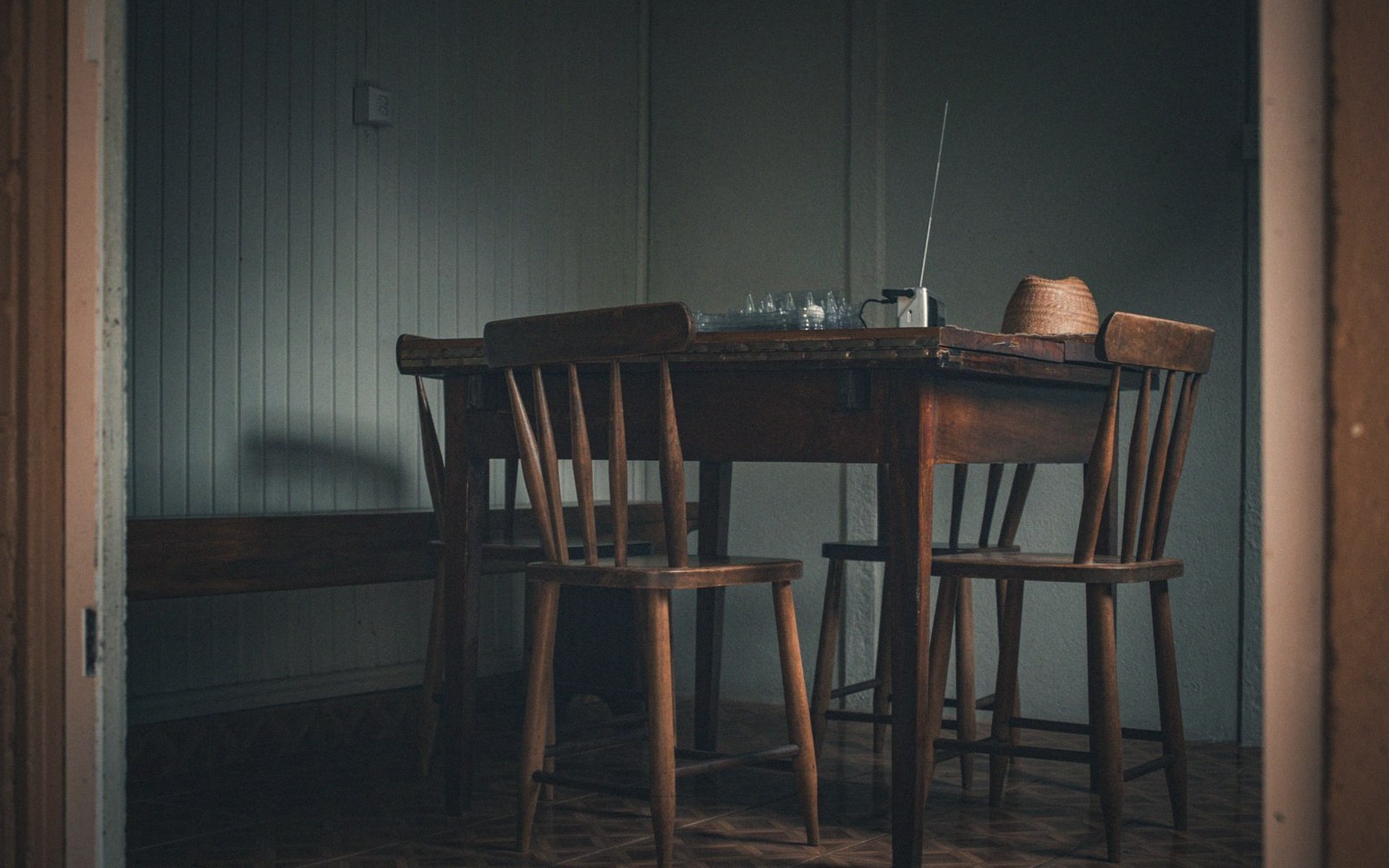 Wooden table and chairs with a small radio antenna in a dim room