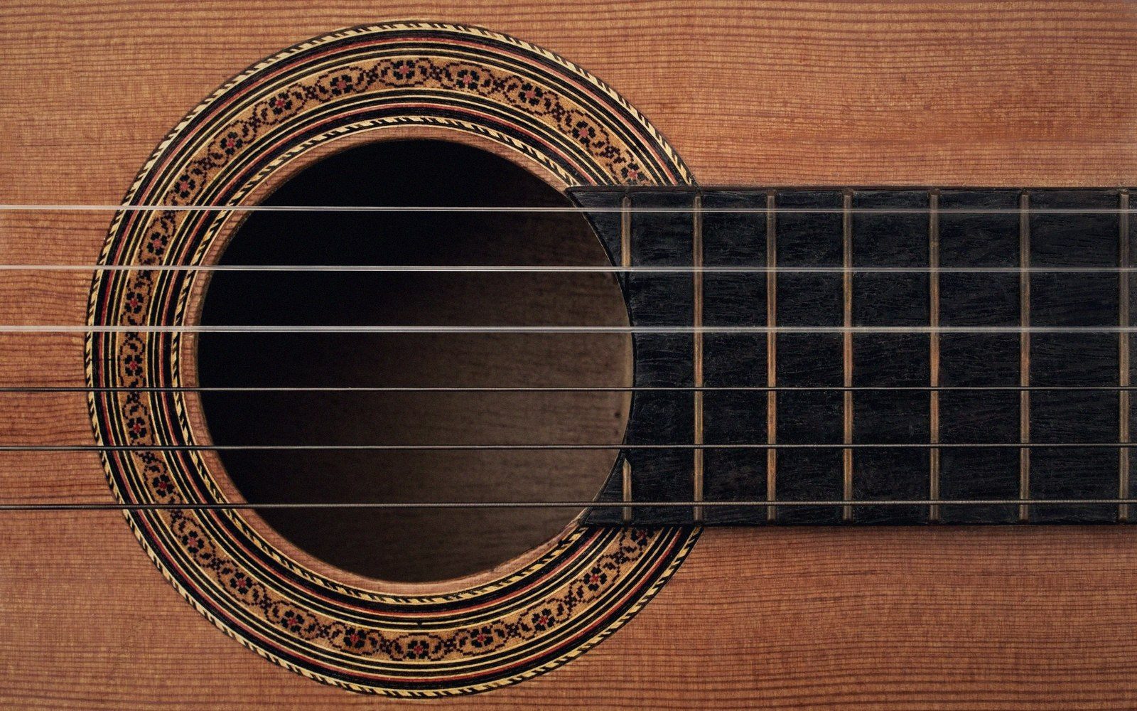A guitar laid flat with screws and a bow across the strings